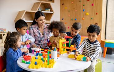 Preschool teacher playing blocks with young students