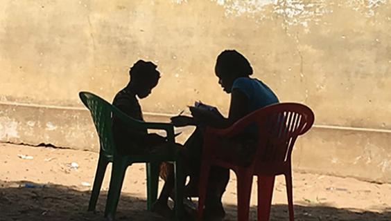 Adult and child reading in silhouette in Mozambique