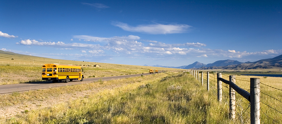 Image of a schoolbus driving through a rural area
