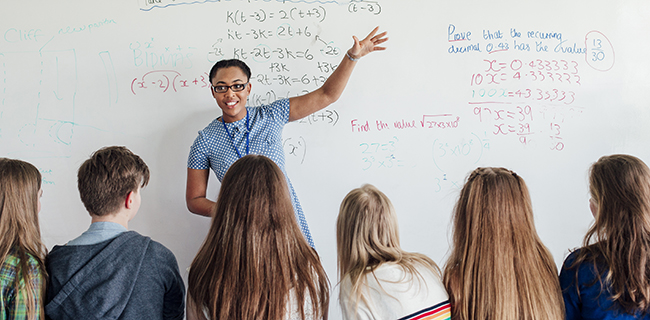 Image of teacher at a whiteboard in front of high school students
