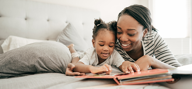 Image of mother with young girl reading on bed together