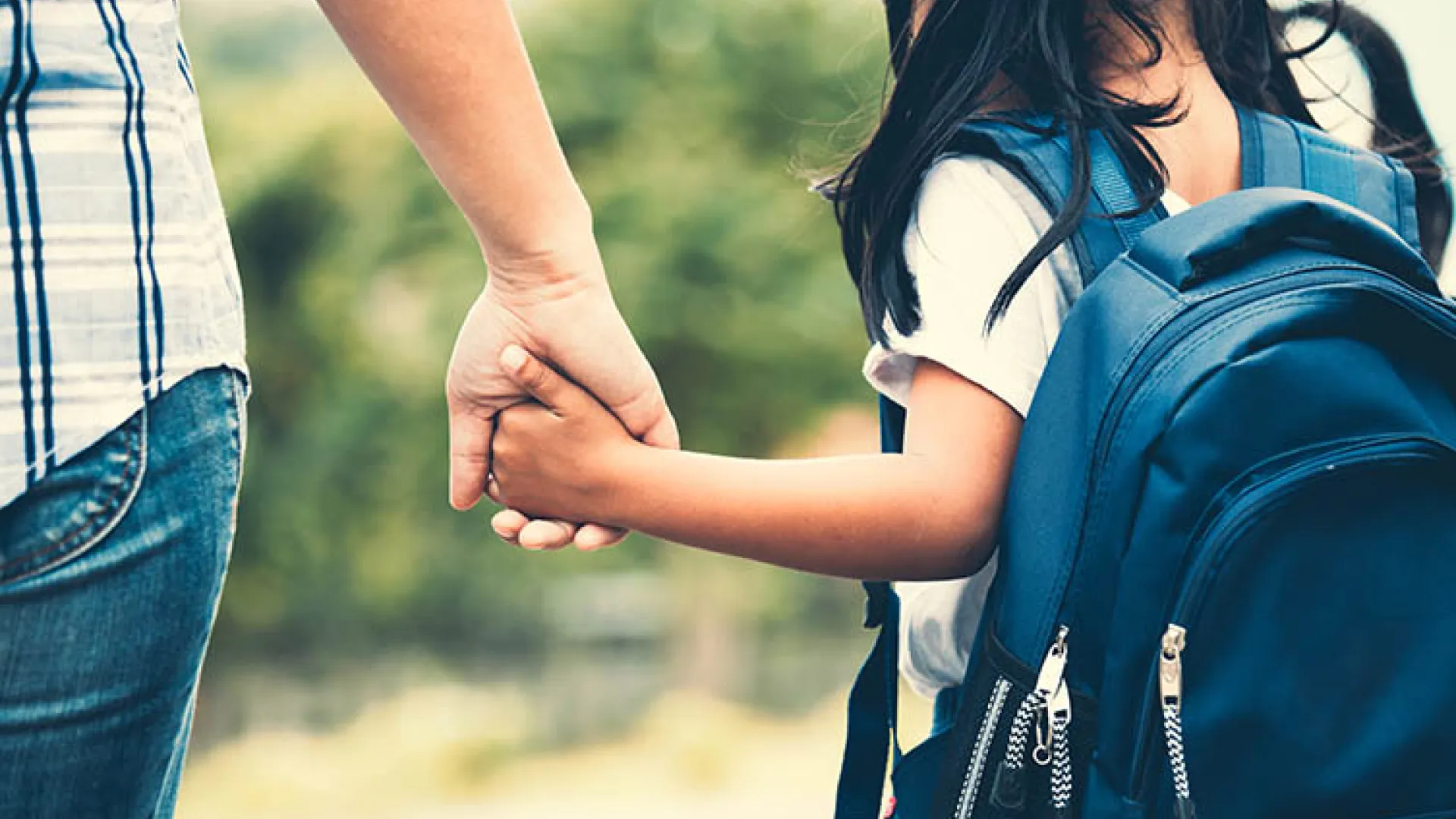 Girl with backpack holding a parent's hand
