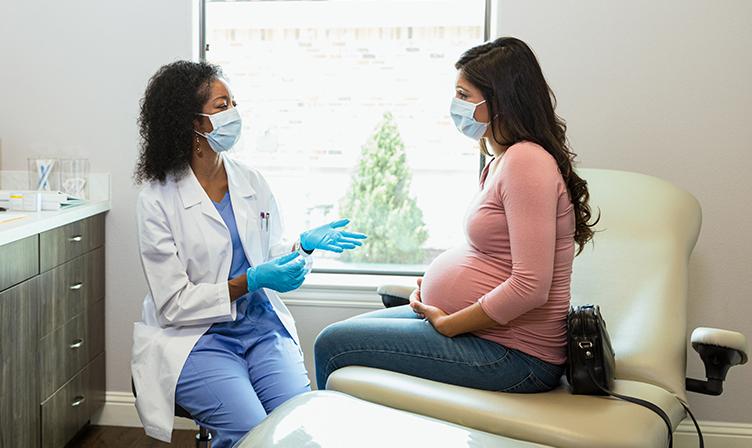 Pregnant patient and doctor wearing masks