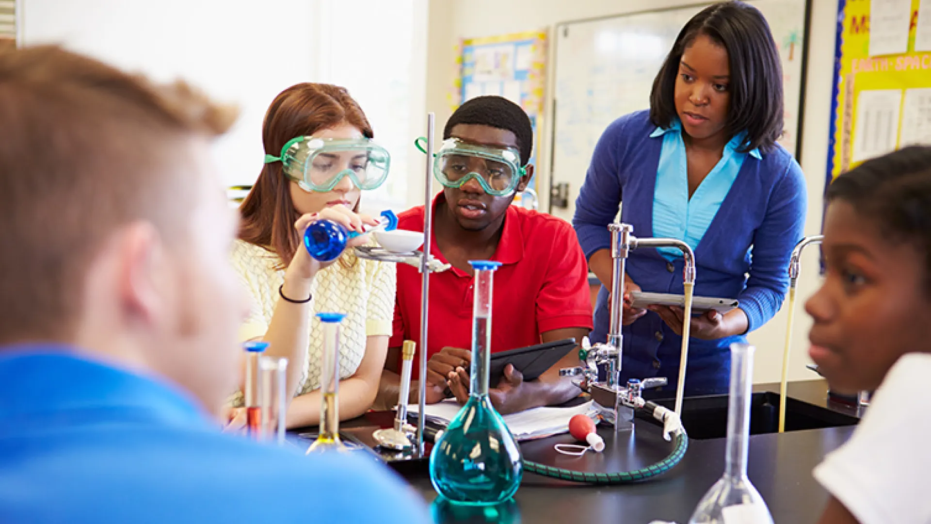 Teacher and high school students in chemistry lab