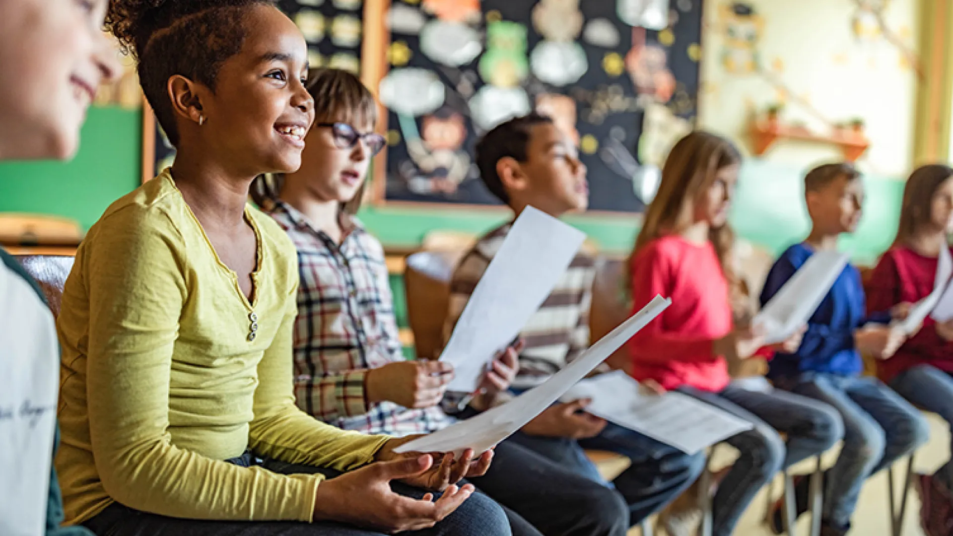 Smiling kids sitting in a row at school