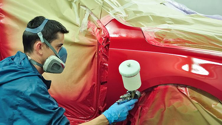 Factory worker painting a car