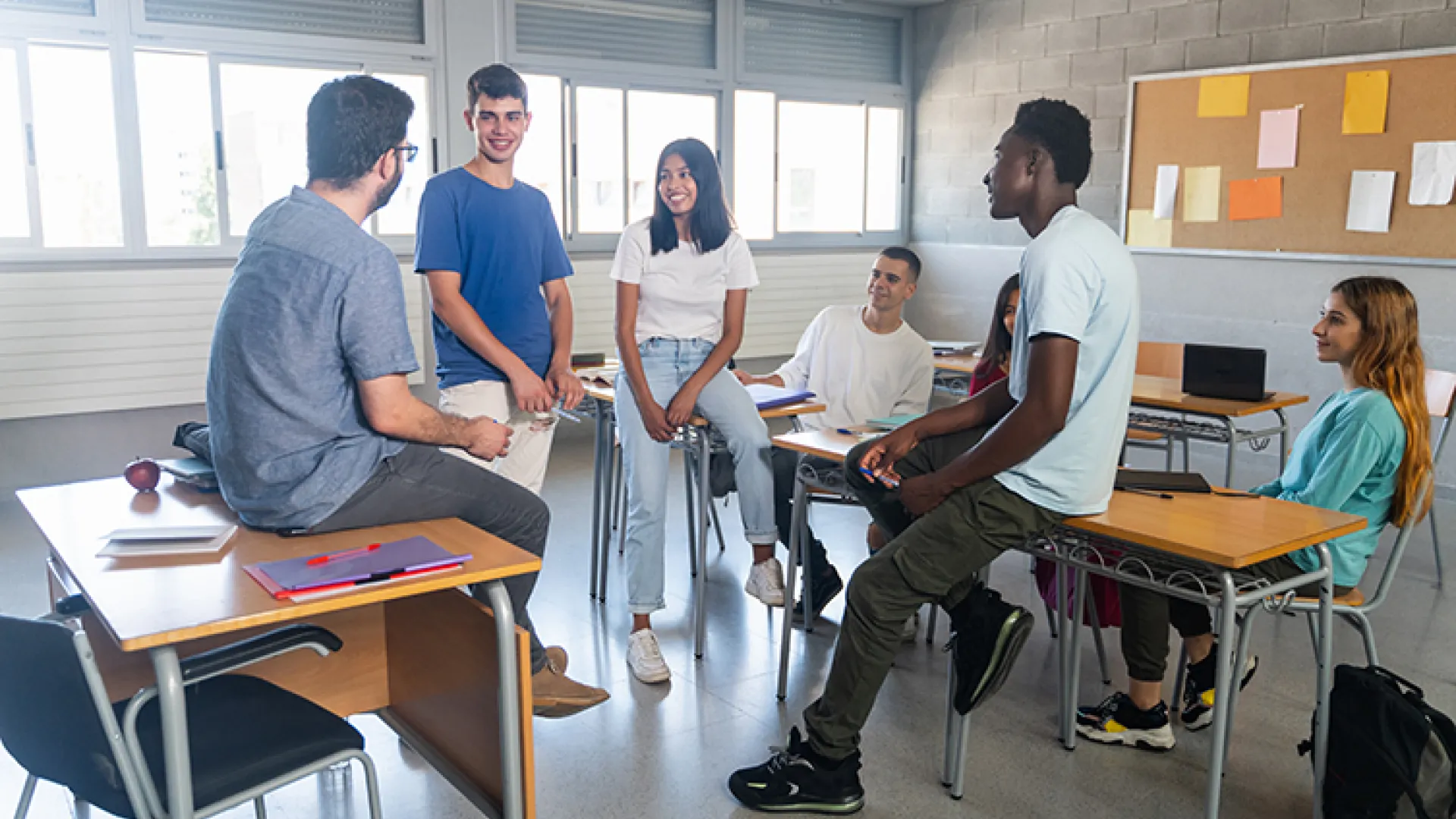 High school students chatting with teacher in classroom