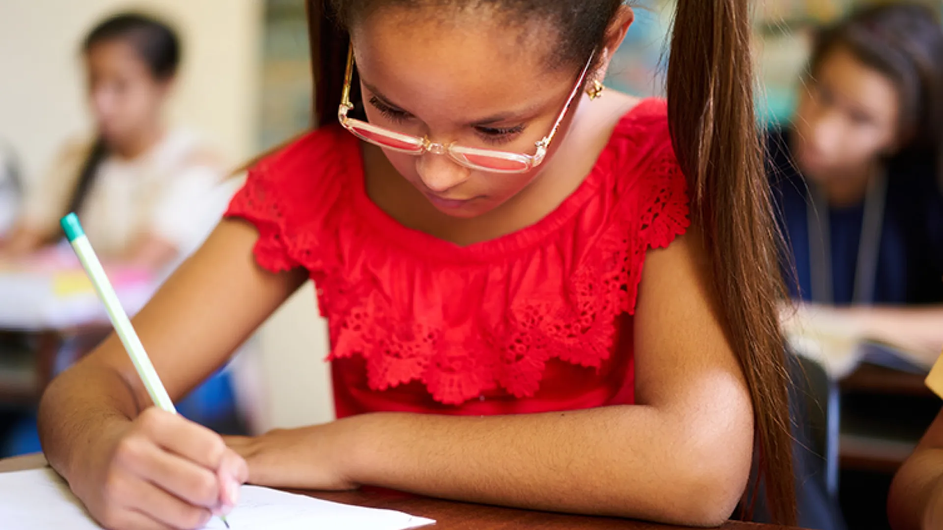 Young female student writing at school desk