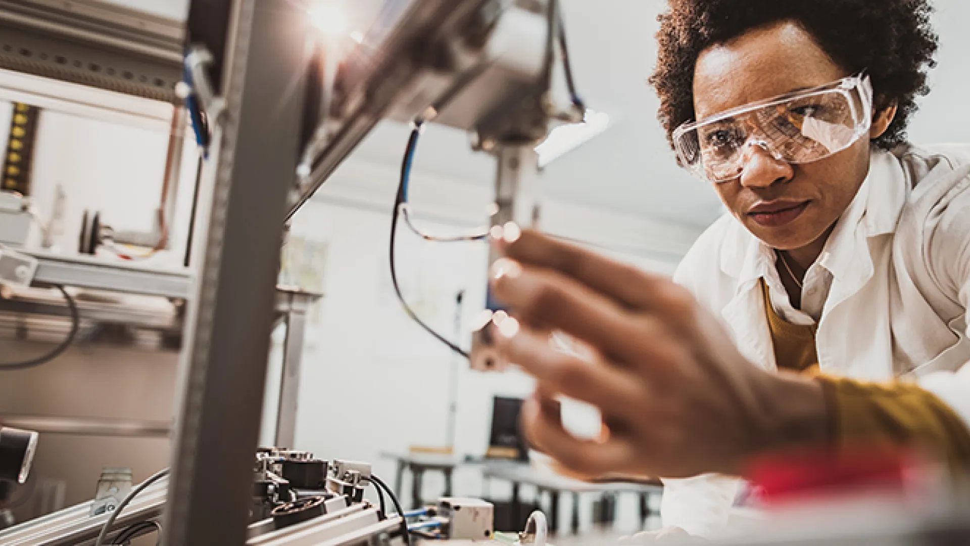Black female engineer working on industrial machine in a laboratory