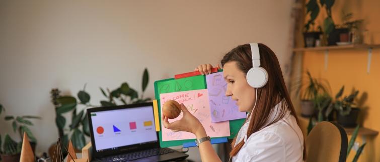Teacher providing online instruction, holding up a shape and board