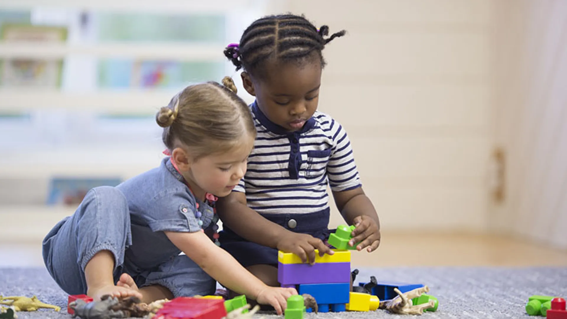Toddlers playing on the floor with blocks