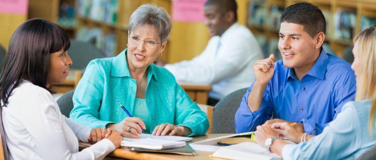 Four teachers meeting in a library 