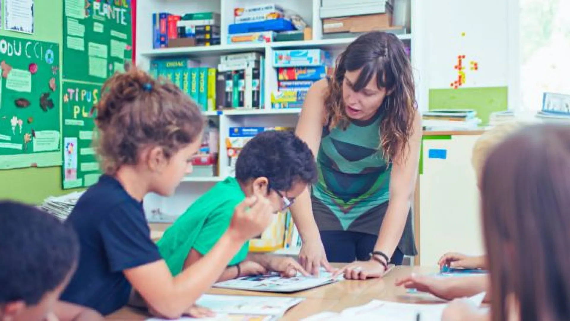 Female teacher working at a table with four elementary students