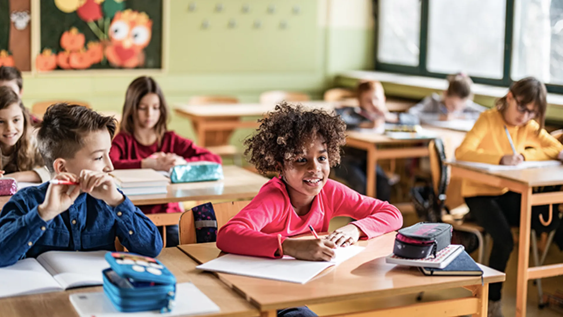 Happy elementary students having a class in the classroom