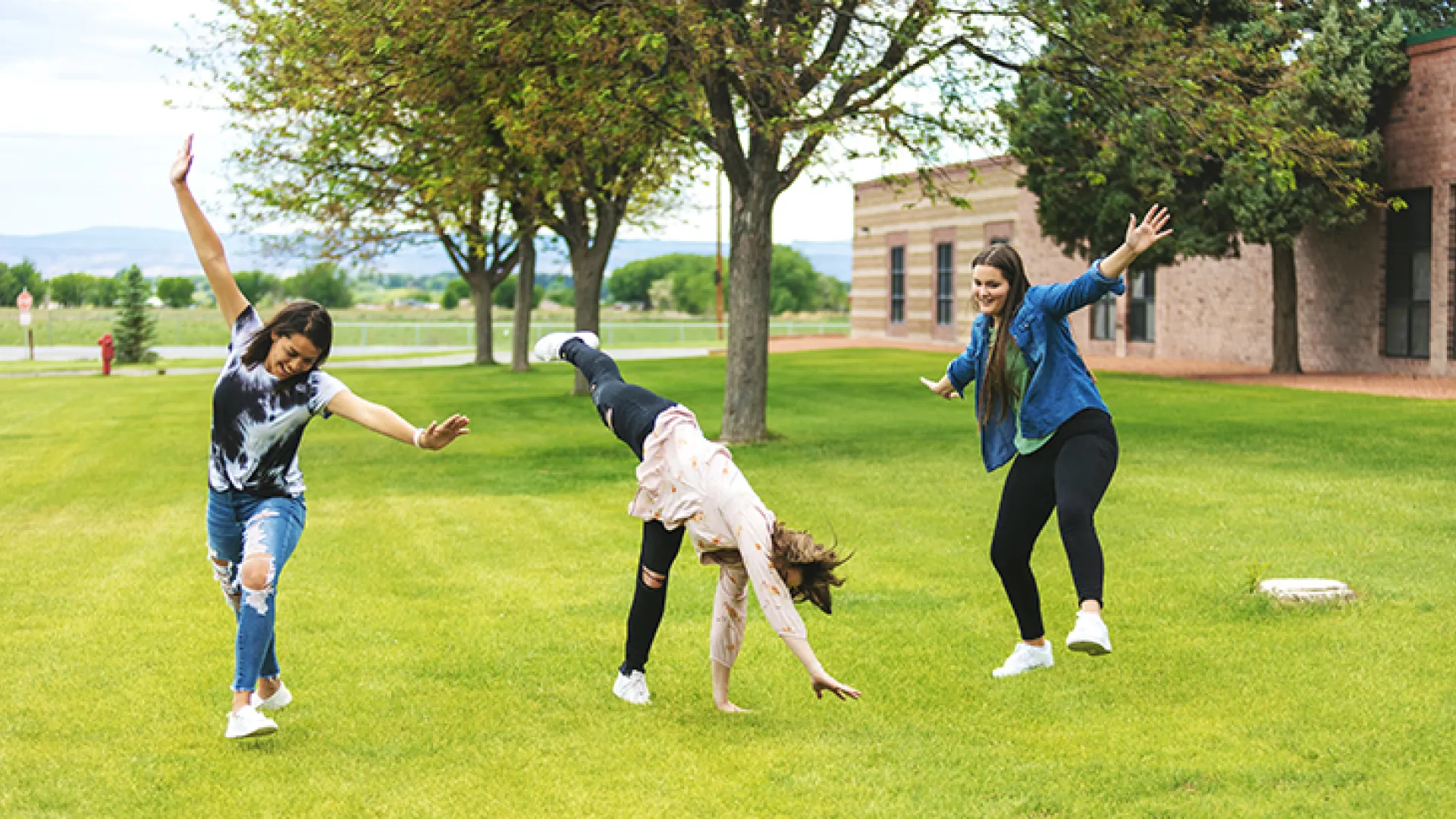Teenage girls cartwheeling outside Colorado school