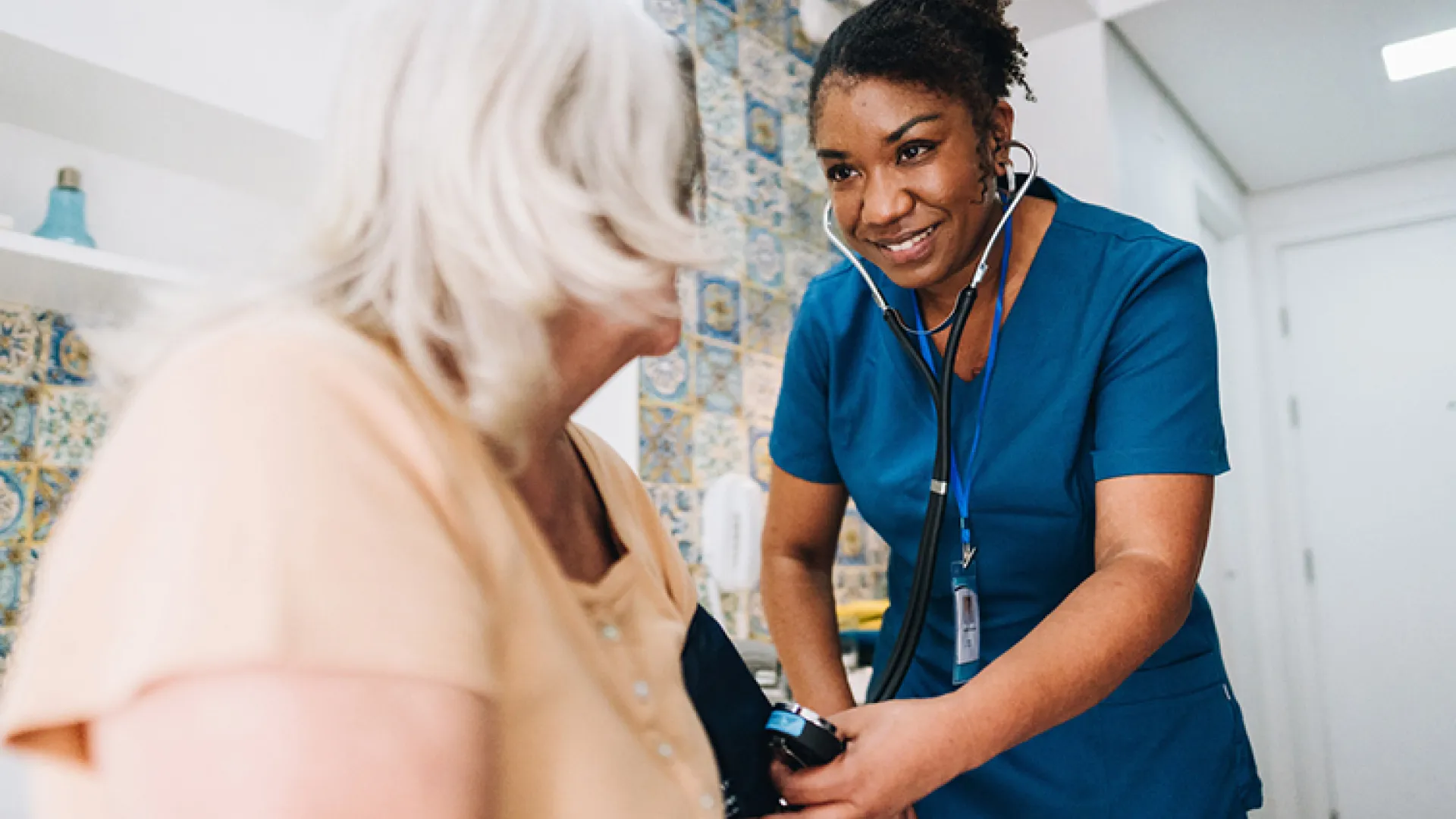 nurse taking blood pressure of elderly patient