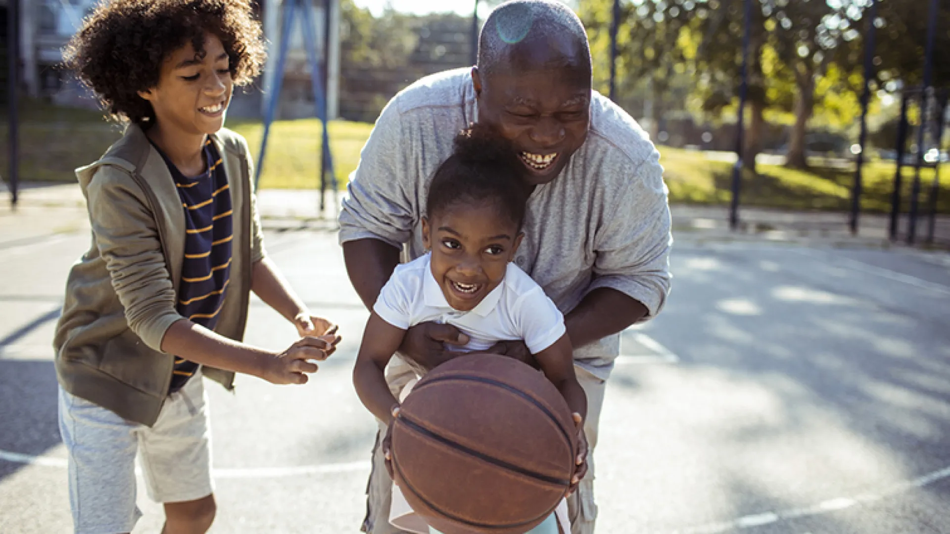 Older man playing basketball with grandchildren