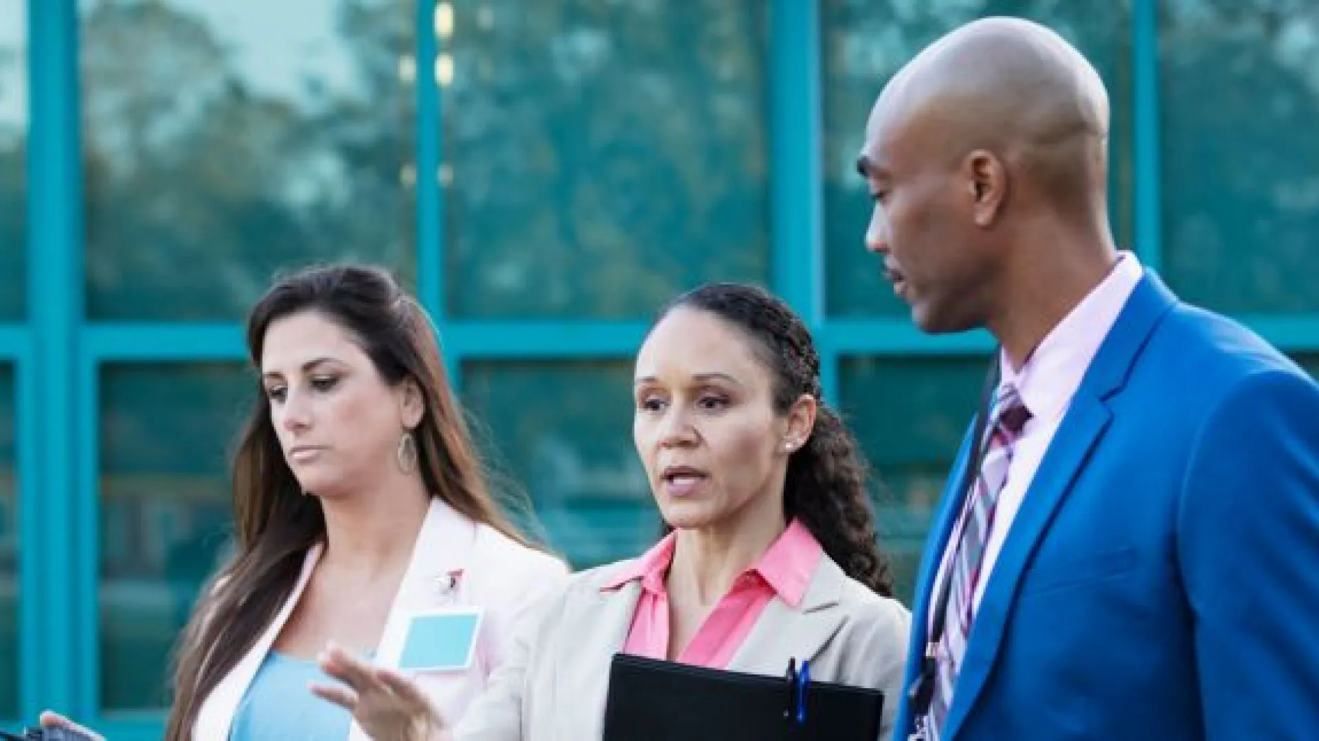 three principals talking outside a school