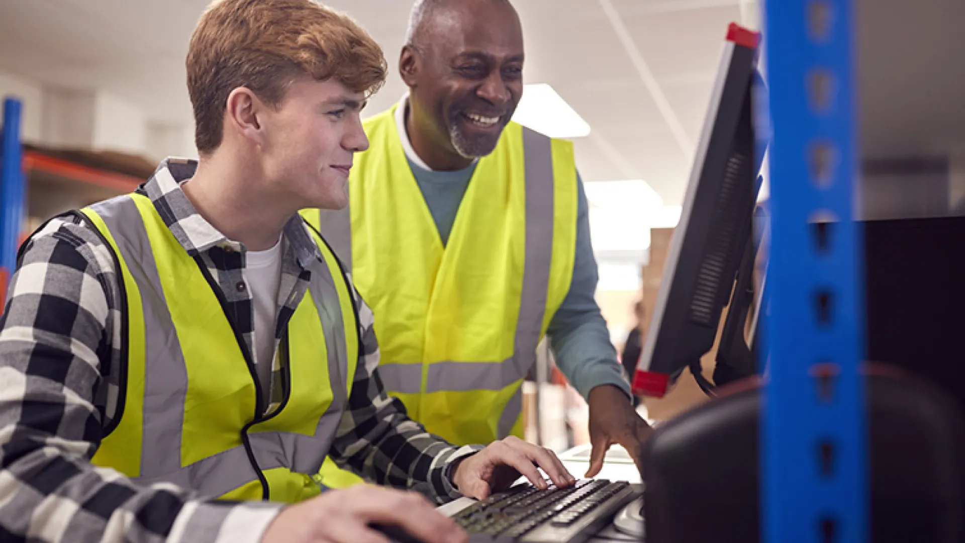intern and supervisor working on computer in warehouse