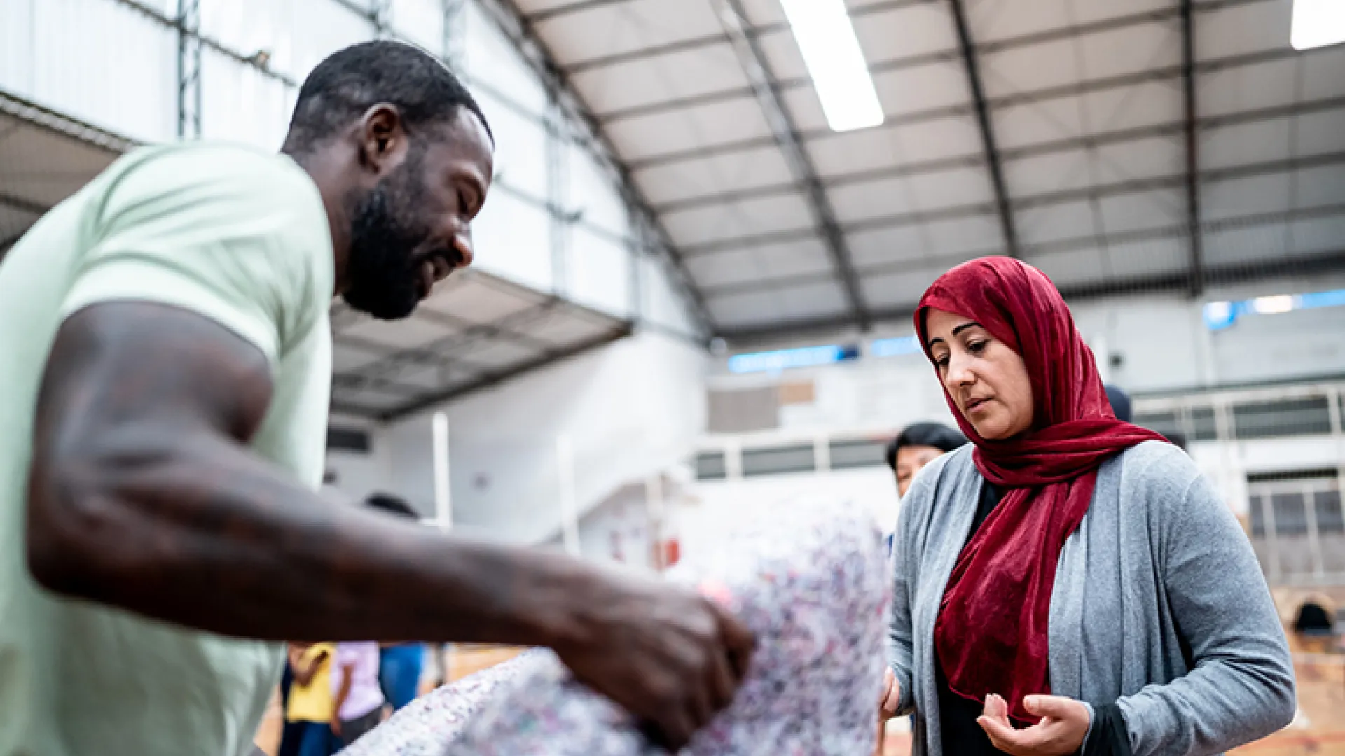 man helping woman in refugee shelter
