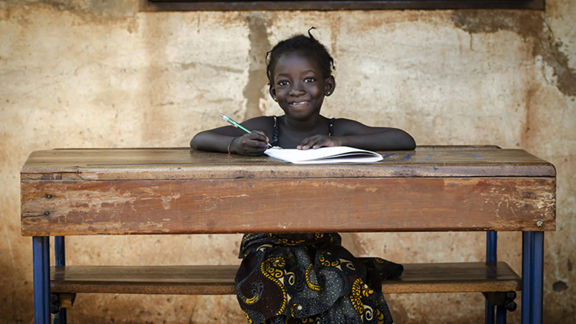 African schoolgirl sitting at desk smiling