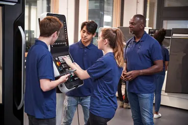 Engineer showing apprentices how to use machine