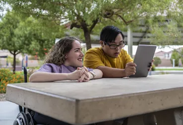 Friends with disabilities looking at an iPad together