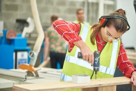 Young woman apprentice using a drill