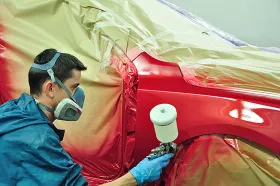 Factory worker painting a car