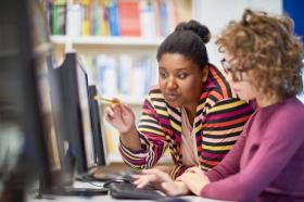 Two teachers looking at a computer monitor together.