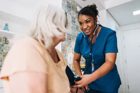 nurse taking blood pressure of elderly patient