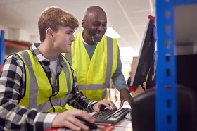 intern and supervisor working on computer in warehouse