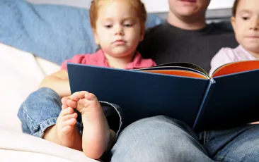 Image of dad and small children reading together