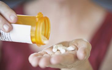 Image of hand with bottle of pills 