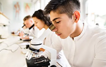 Image of Hispanic teenager at a microscope