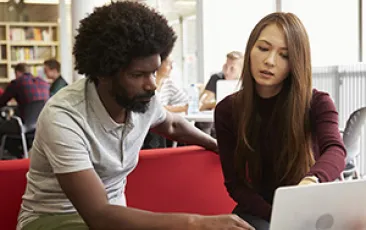 Image of young adults conferring over a laptop