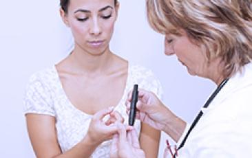 doctor testing young woman's glucose level 