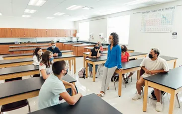 Image of socially distanced teachers in a classroom, wearing masks