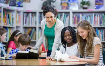 teacher in library working with students