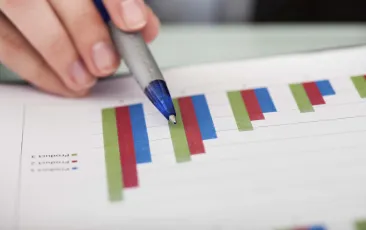 Pen and hand pointing at graphs on page