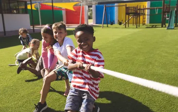 Young kids pulling on a rope together outside