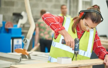 Young woman apprentice using a drill