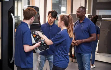 Engineer showing apprentices how to work a machine