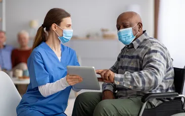 Older male patient with doctor, both wearing masks