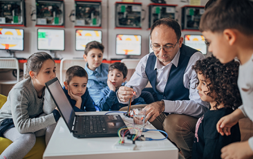 Teacher showing computer experiments to children 