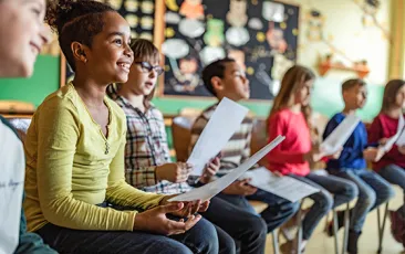 Smiling kids sitting in a row at school