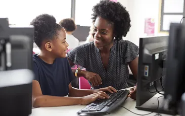 Teacher and student at desktop computer