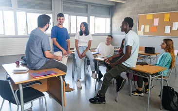 High school students chatting with teacher in classroom