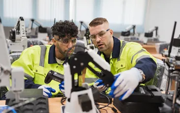 Two engineer man learning control and repair arm robot in class