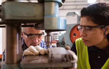 Apprentice and mentor with heavy machinery